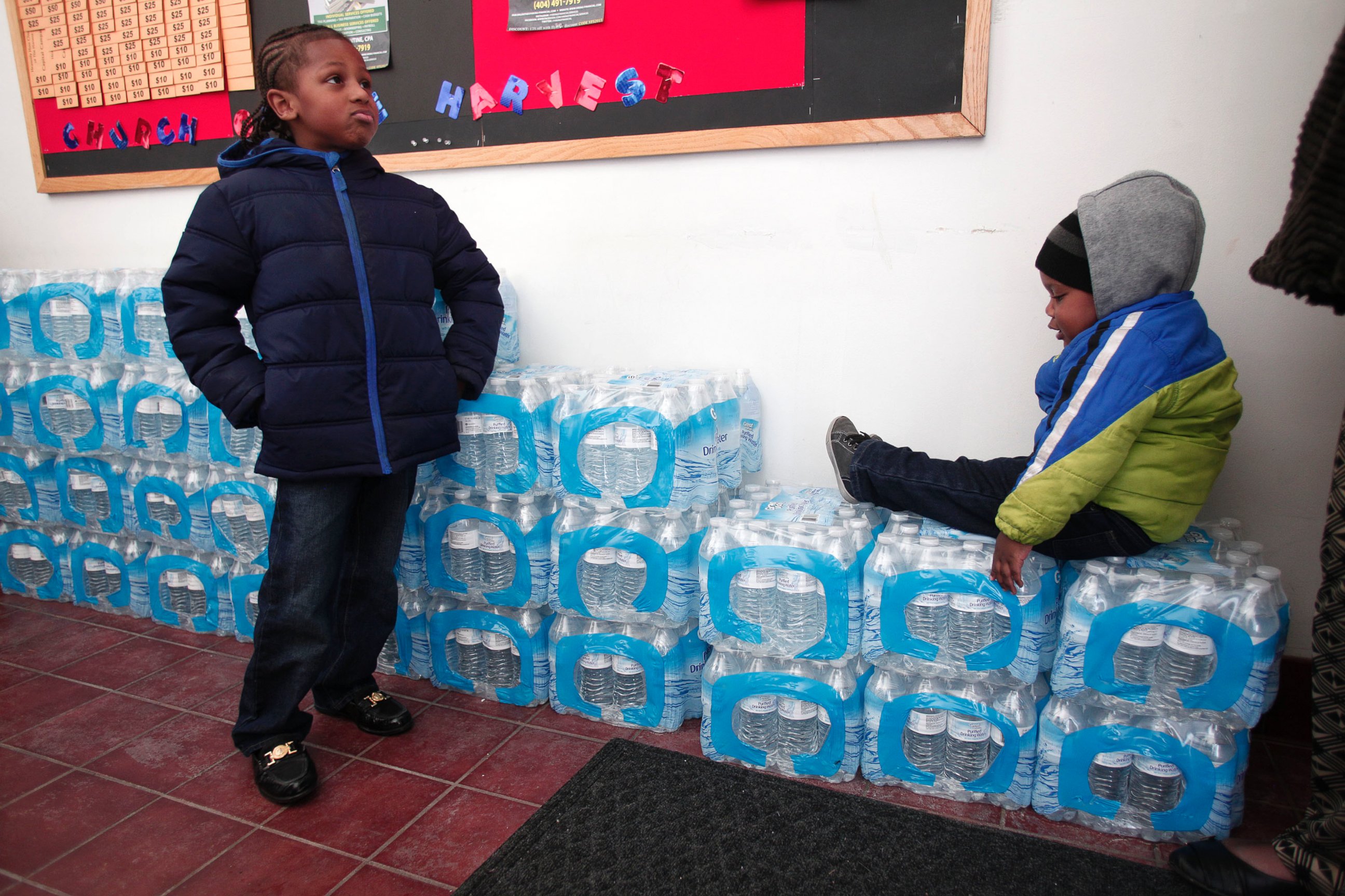 PHOTO: Justin Roberson (L), age 6, of Flint, Michigan and Mychal Adams, age 1, of Flint wait on a stack of bottled water at a rally where the Rev. Jesse Jackson was speaking about the water crisis on Jan. 17, 2016 in Flint, Michigan.