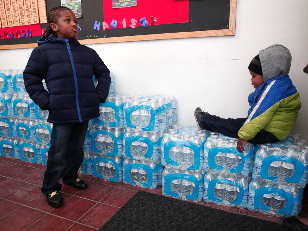 PHOTO: Justin Roberson (L), age 6, of Flint, Michigan and Mychal Adams, age 1, of Flint wait on a stack of bottled water at a rally where the Rev. Jesse Jackson was speaking about the water crisis on Jan. 17, 2016 in Flint, Michigan.
