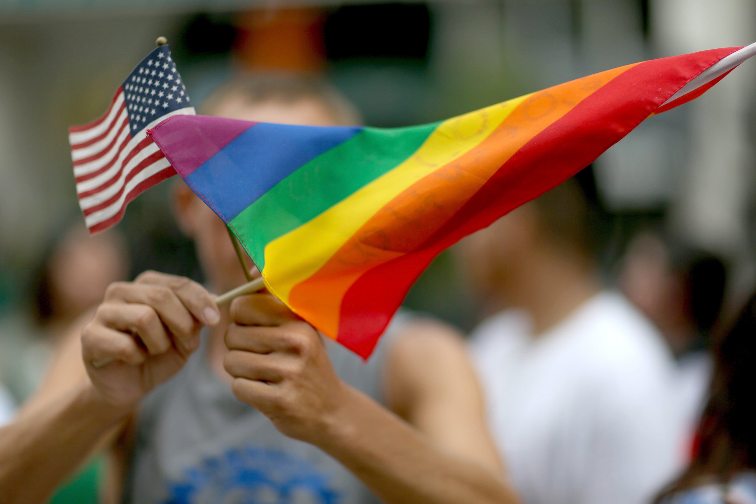 PHOTO: A protester holds an American flag and rainbow flag in front of the Miami-Dade Courthouse to show his support of the LGBTQ couples, July 2, 2014, in Miami.