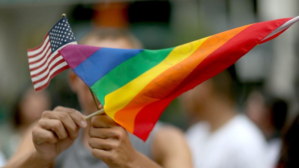 A protester holds an American flag and rainbow flag in front of the Miami-Dade Courthouse to show his support of the LGBTQ couples, July 2, 2014, in Miami.