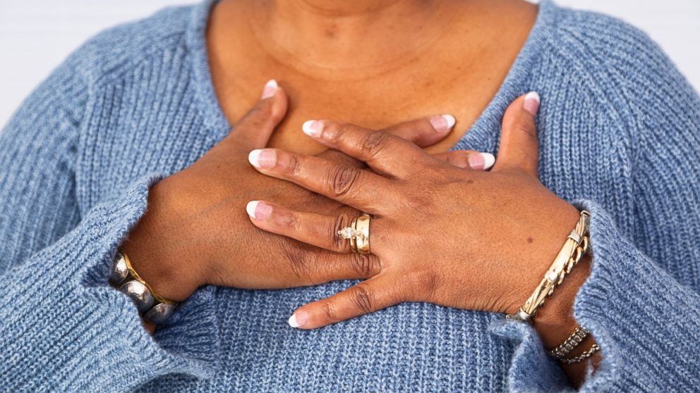 In this stock image, a woman is pictured experiencing possible heart attack symptoms. 