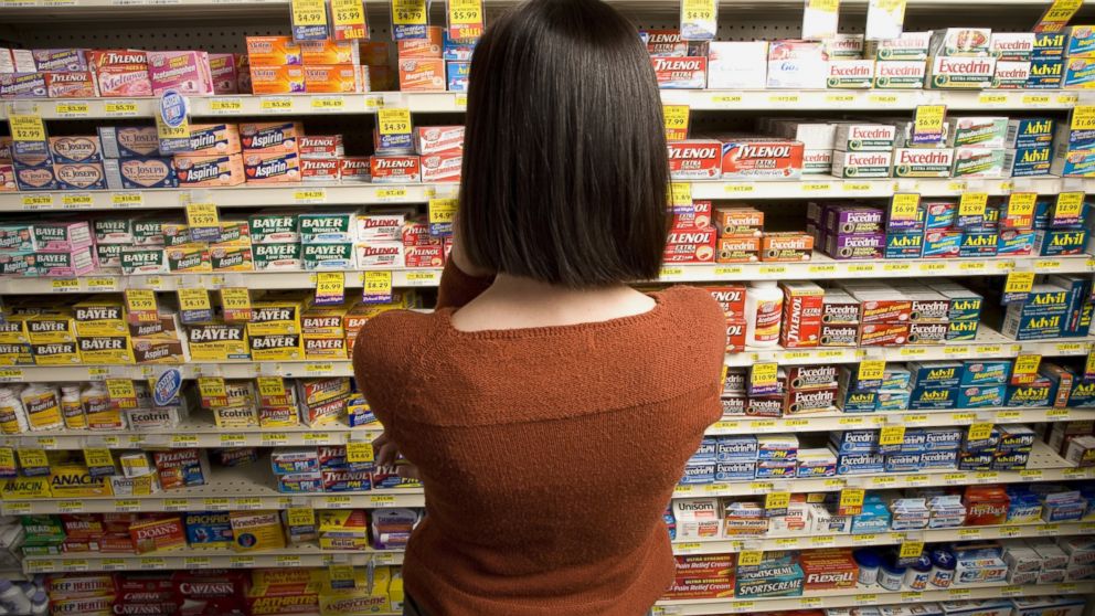 A woman browses for medicine at a pharmacy.
