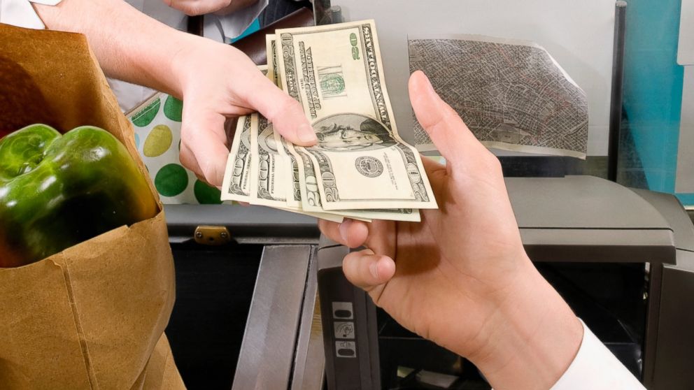 A customer is pictured handing a cashier money in this stock image.
