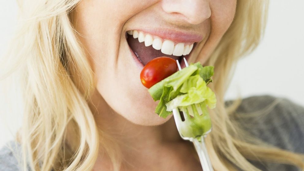 A woman is pictured eating salad in this stock image. 