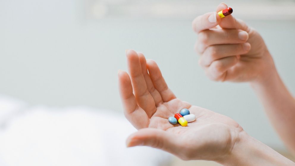 In this stock image, a woman is pictured taking pills.