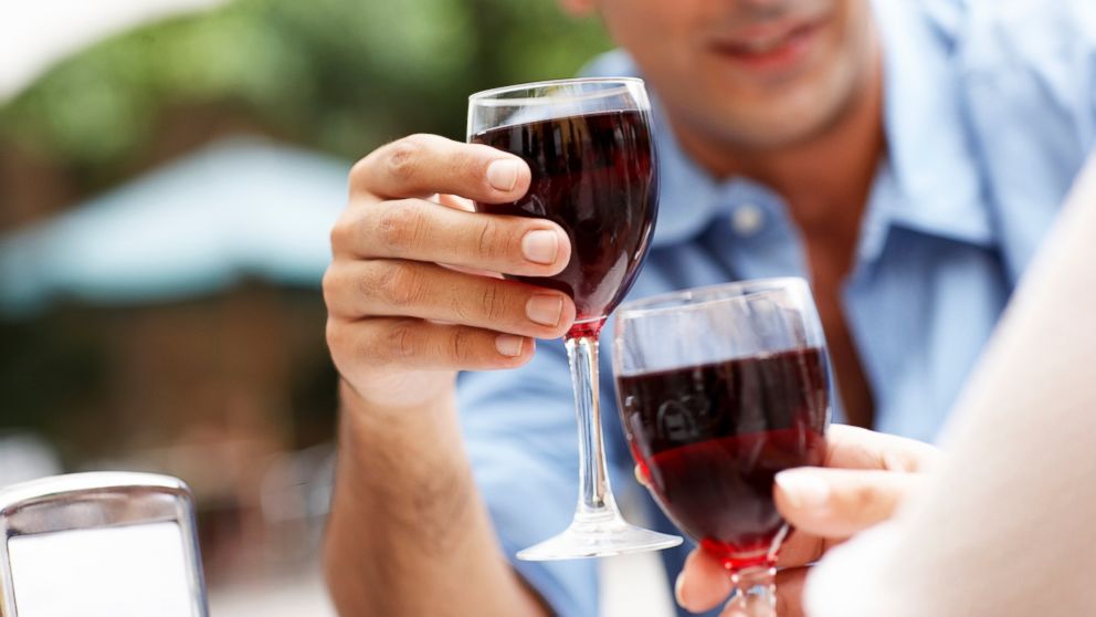 In this stock image, a couple is pictured with two glasses of red wine. 