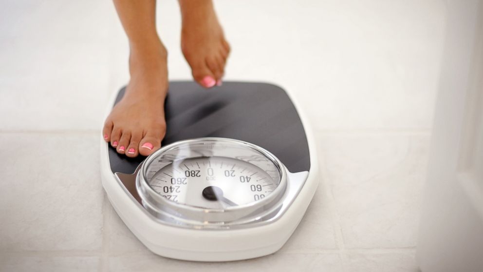 In this undated stock image, a woman is pictured stepping on a scale.