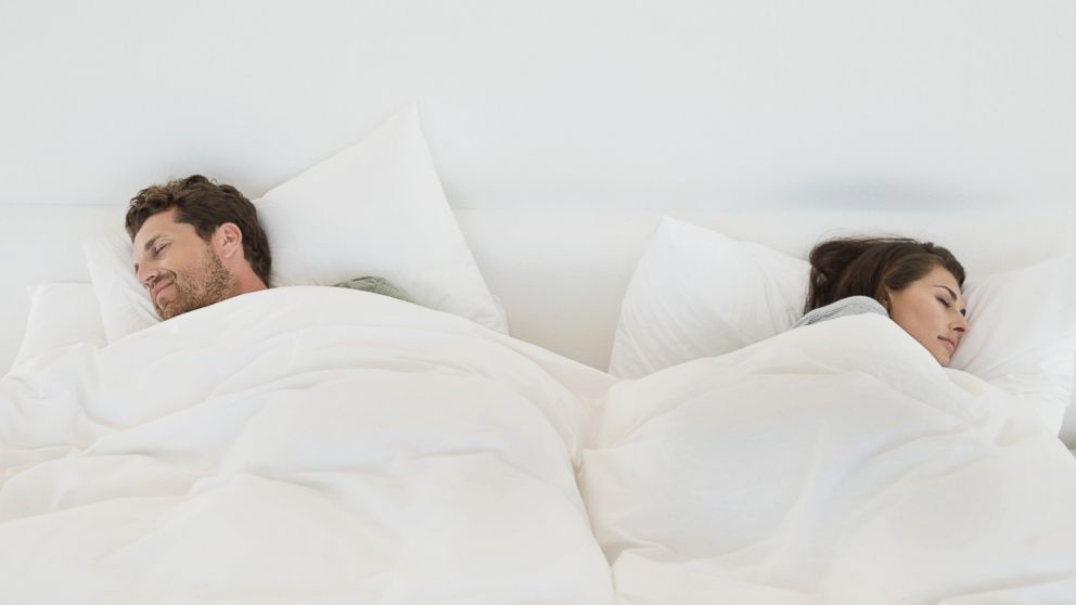 In this stock image, a couple is pictured sleeping in bed. 