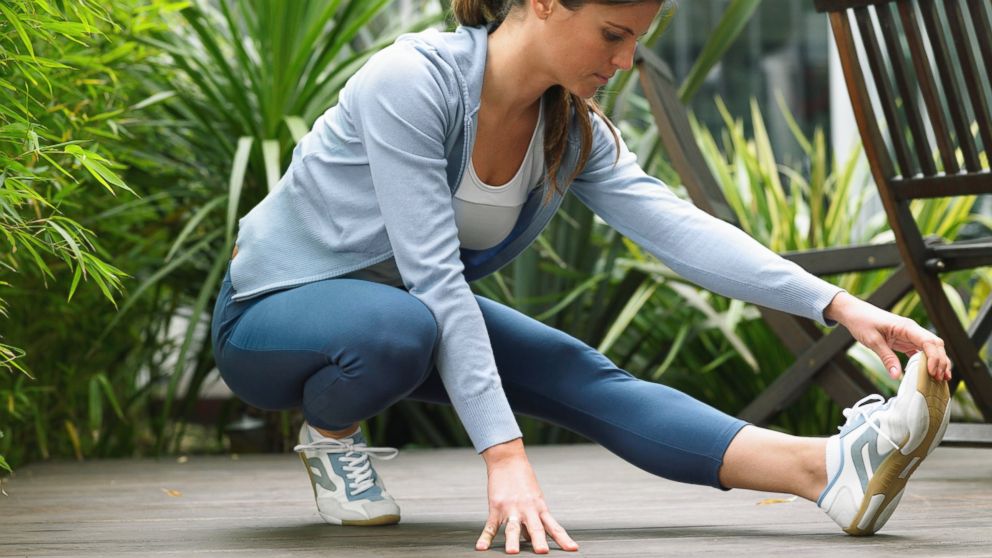 In this stock photo, a woman wearing running clothes is pictured stretching. 