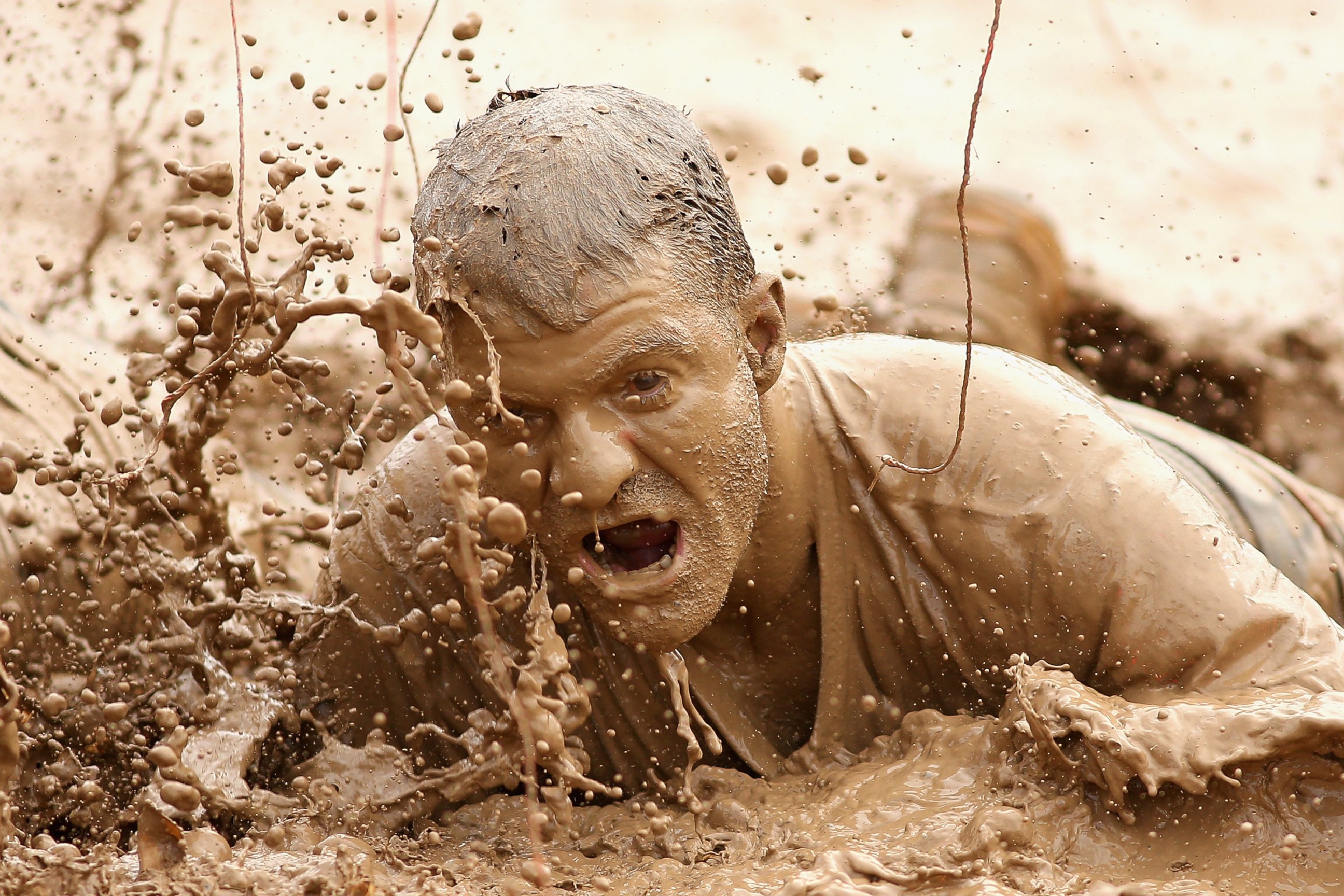 PHOTO: A competitor crawls through mud during Toughmudder at Phillip Island Grand Prix Circuit, March 23, 2014 in Phillip Island, Australia.