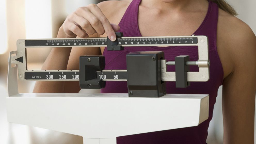 In this stock image, a woman is pictured using a scale. 