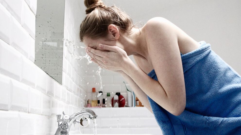 A woman washes her face with water in this stock photo.