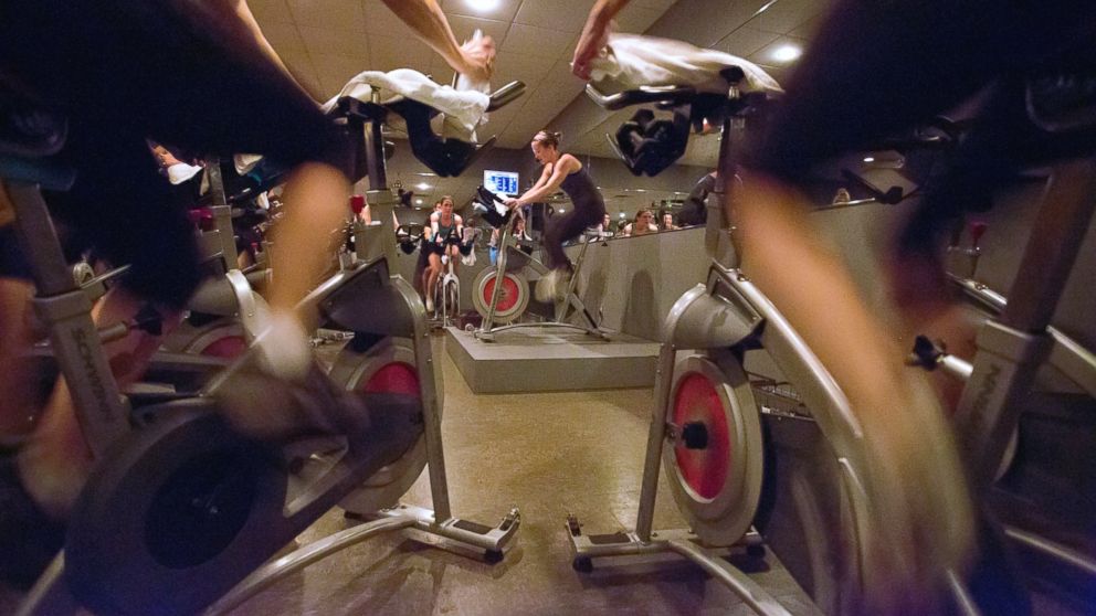 Instructor/trainer Carolyn Williams is framed by stationary bikes as she leads a 6 a.m. spin class at RÂ�eve Cycling Studio5. 