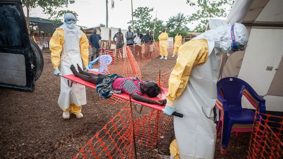 PHOTO: Two medical staff are bringing a weak patient who has been in contact with people infected with Ebola to the admission at MSF Ebola Treatment Centre in Kailahun, Sierra Leone.