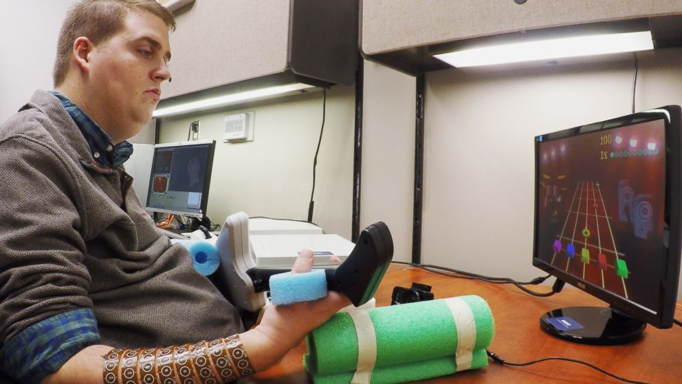 PHOTO: Ian Burkhart, 24, plays a guitar video game as part of a study into neural bypass technology that allowed him to regain functional use of his paralyzed hand. 