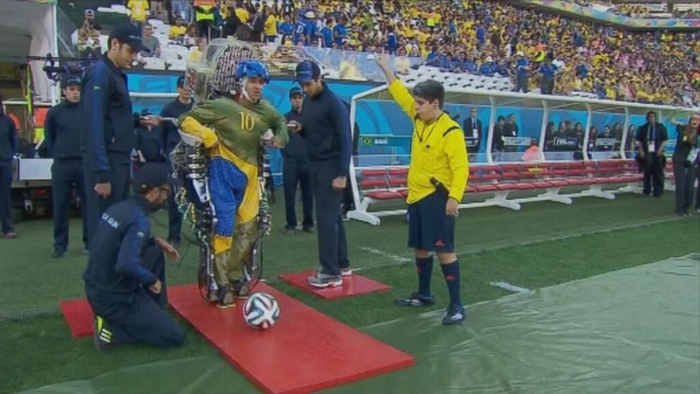 PHOTO: A paraplegic man wears an exoskeleton kicks a soccer ball 