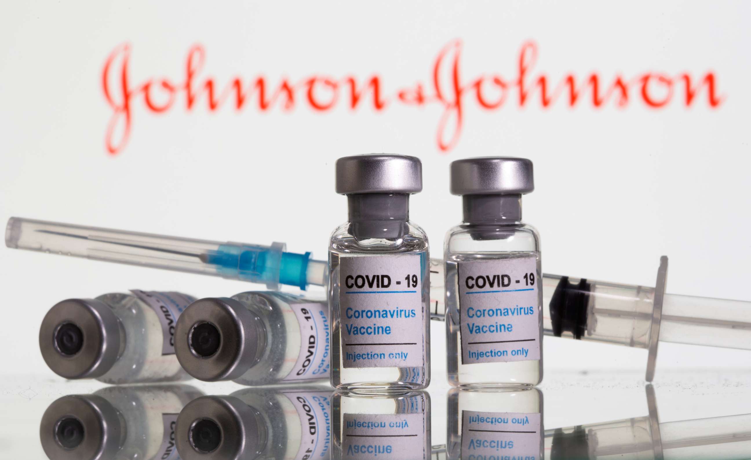 FILE PHOTO: Vials labelled "COVID-19 Coronavirus Vaccine" and syringe are seen in front of displayed Johnson & Johnson logo in this illustration taken, February 9, 2021. 