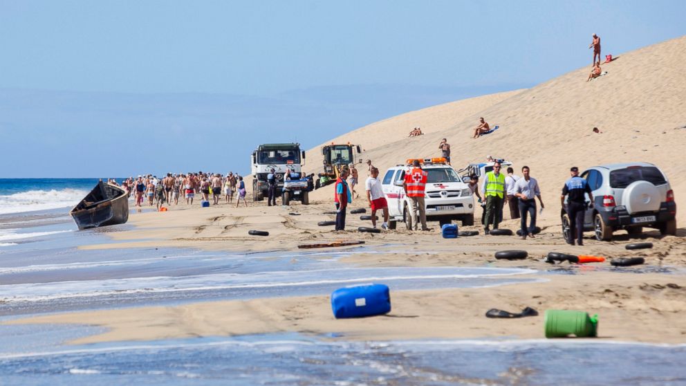 PHOTO: People walk near emergency personnel and the fishing boat used by people who arrived by boat from Africa, at Maspalomas beach on Gran Canaria, Spain's Canary Islands, Nov. 5, 2014.  