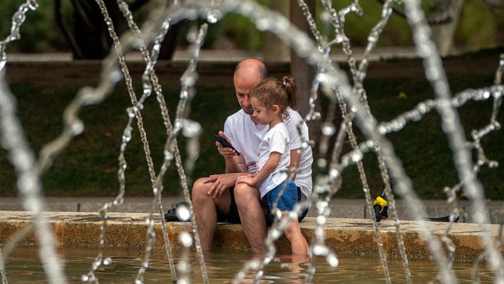 A man and a girl cool off in a fountain in a park during a heatwave in Madrid, Spain, Saturday, Aug. 14, 2021. Temperatures were set to hit a maximum of 46 degrees Celsius in Spain on Saturday, as the country sweltered on the hottest day of the year 