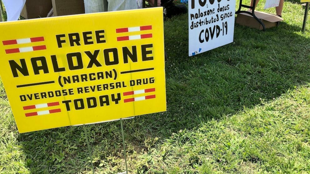 FILE - Signs are displayed at a tent during a health event on June 26, 2021, in Charleston, W.Va. Last July, a federal judge in West Virginia heard closing arguments in the first lawsuit to go to trial over the U.S. opioid addiction epidemic. With an