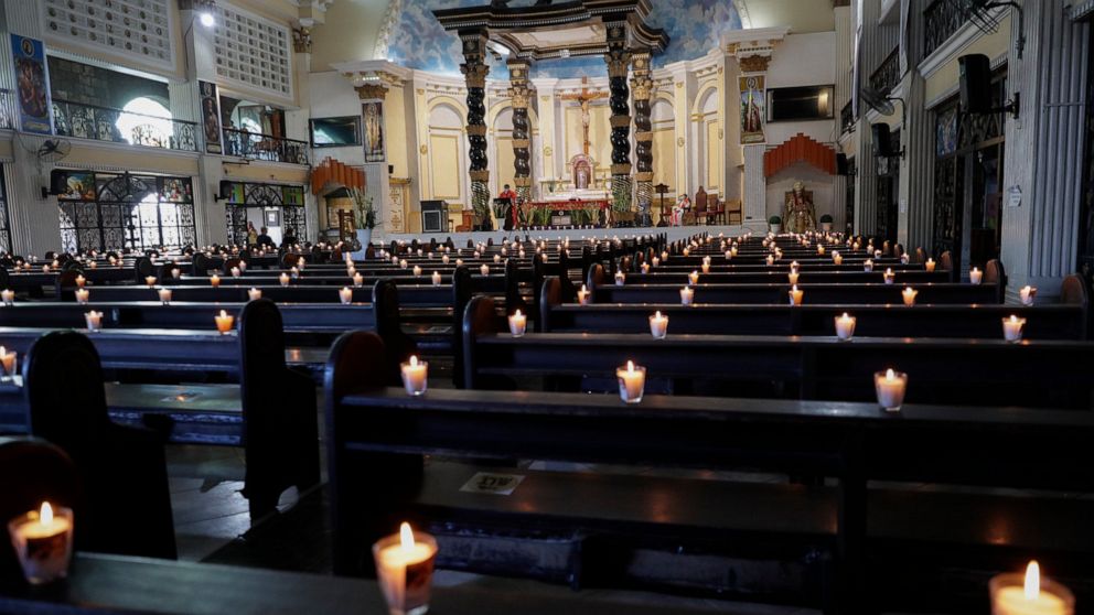 Lighted candles are placed on empty pews as Catholic priest presides over a Palm Sunday mass to prevent the spread of the coronavirus at the Saint Peter Parish Church in Quezon city, Philippines on March 28, 2021. The government banned religious acti