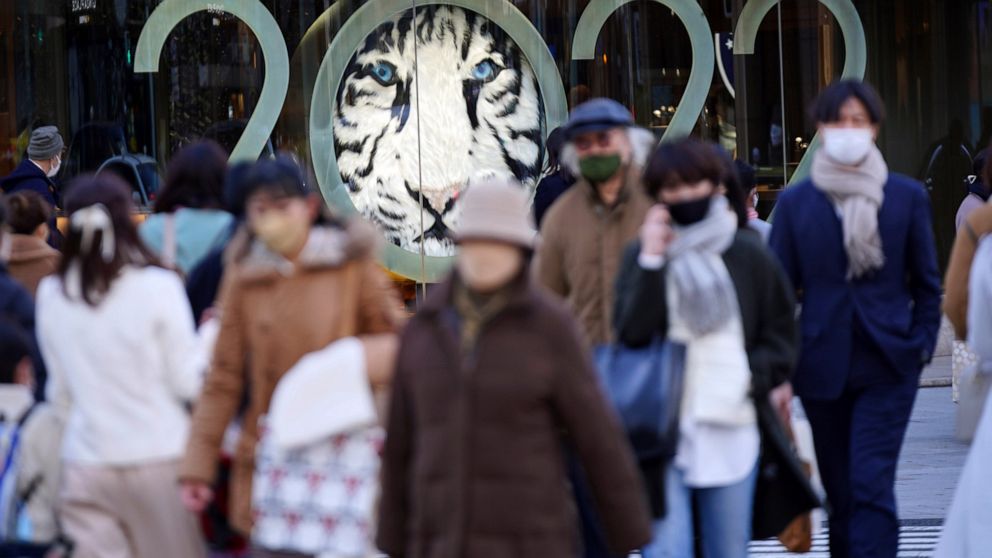 FILE - People wearing protective masks to help curb the spread of the coronavirus walk along a pedestrian crossing Tuesday, Jan. 18, 2022, in Tokyo. The Japanese government announced Wednesday, Jan. 19, 2022, it will place Tokyo and a dozen other are