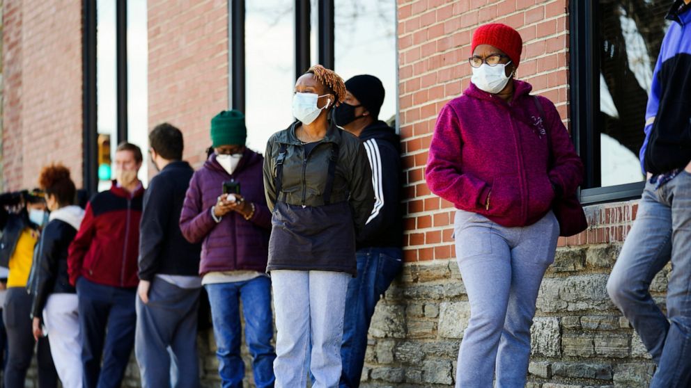 FILE - In this March 29, 2021, file photo, people wearing face masks as a precaution against the coronavirus wait in line to receive COVID-19 vaccines at a site in Philadelphia. Nearly half of new coronavirus infections nationwide are in just five st