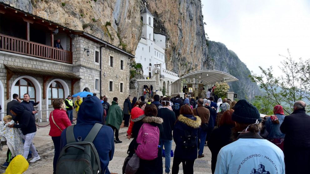 In this photo taken Tuesday, May 12, 2020, people wait in a queue in front of the Christian Orthodox monastery of Ostrog, 30 kilometers northwest of the Montenegrin capital Podgorica. Serbia has strongly protested the detention of eight Serbian Ortho