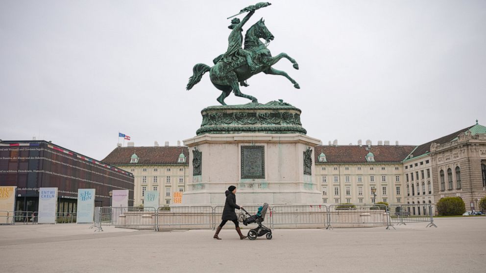 FILE - A woman pushes a baby stroller in Vienna, Austria, Monday, Nov. 22, 2021. As remaining cities and regions in Austria reopen restaurants and hotels, the country is reporting fewer than 2,000 new coronavirus cases. This is the lowest number sinc