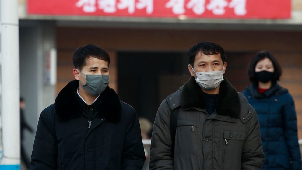 People wearing face masks walk on the street near the Pyongyang railway station in Pyongyang, North Korea, Thursday, Jan. 27, 2022. The red banner says, "Implementation of decisions of the Forth Plenary Meeting of the Eighth Central Committee of Work