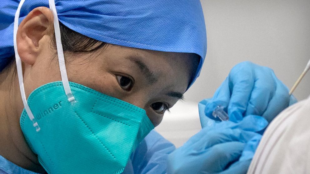 FILE - In this Jan. 15, 2021, file photo, a medical worker gives a coronavirus vaccine shot to a patient at a vaccination facility in Beijing. China is aiming to vaccinate 70-80% of its population by mid-2022, the head of the country's Center for Dis