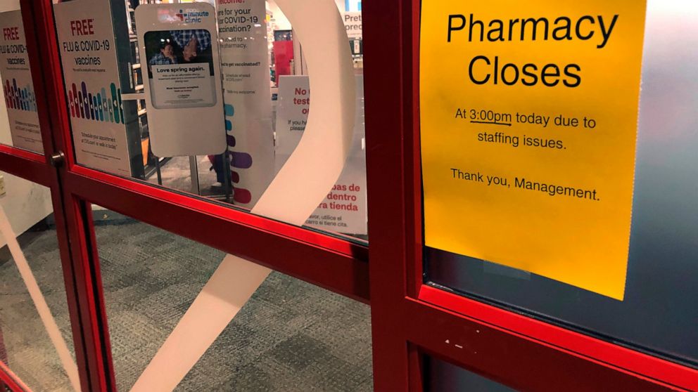 A sign is posted outside a CVS pharmacy on Thursday, Dec. 2, 2021 in Indianapolis. A rush of vaccine-seeking customers and staff shortages are squeezing drugstores around the country. That has led to frazzled workers and even temporary pharmacy closu