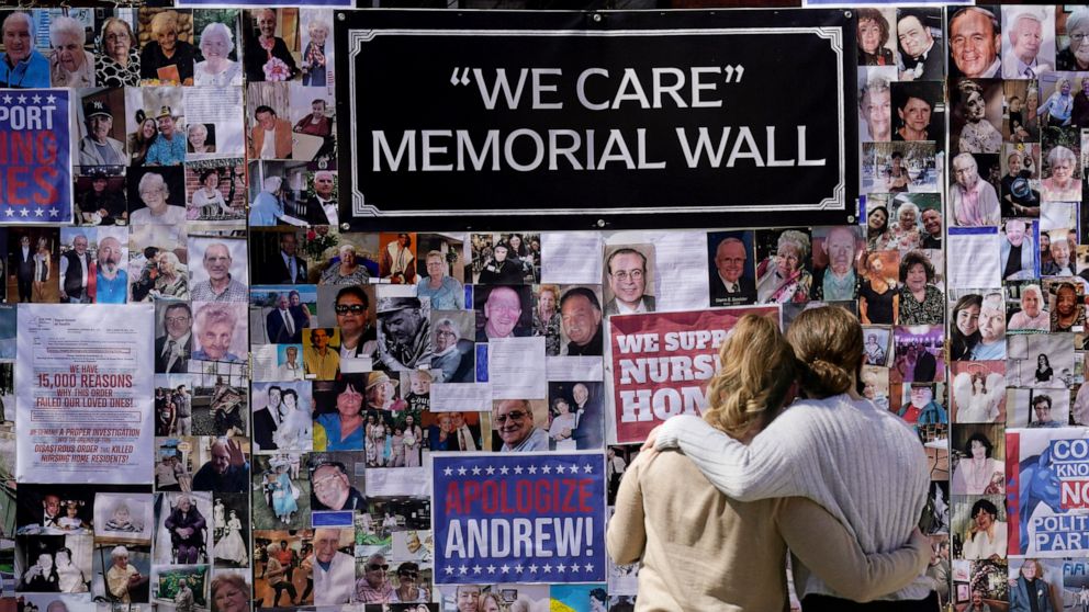 FILE - In this March 21, 2021 file photo, Theresa Sari, left, and her daughter Leila Ali look at a section of a memorial wall after a news conference in New York Sari's mother, Maria Sachse, was a nursing home resident and died from COVID-19. After a
