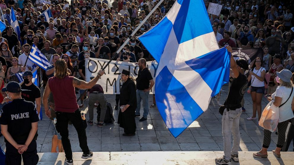 Anti-vaccine protester hold Greek flags during demonstration at Syntagma square, central Athens, on Wednesday, July 14, 2021. Some thousands of anti-vaccine demonstrators gathered in Greece's two largest cities Wednesday over plans to make the vaccin