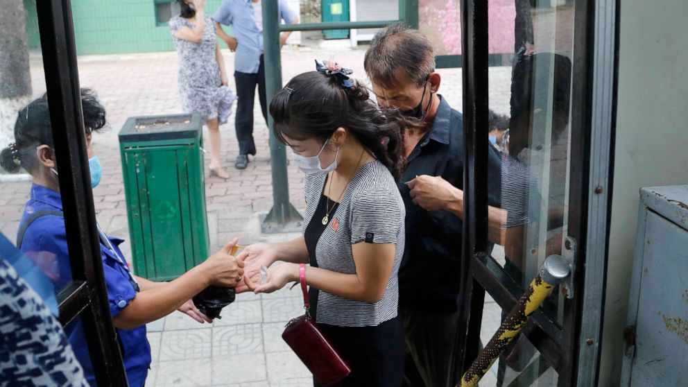 A passenger wearing a face mask to help curb the spread of the coronavirus is disinfected her hands before getting on a trolley bus in Pyongyang, North Korea, Thursday, Aug. 13, 2020. (AP Photo/Jon Chol Jin)
