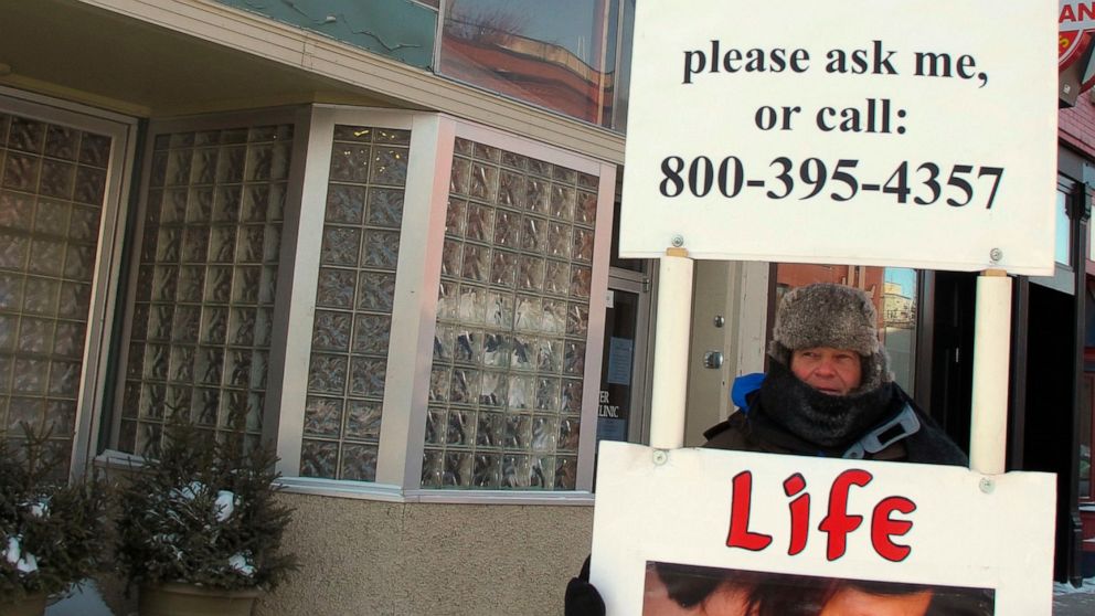 FILE - In this Feb. 20, 2013 file photo, an abortion protester stands outside the Red River Valley Women's Clinic in Fargo, N.D. North Dakota's sole abortion clinic filed a federal lawsuit Tuesday, June, 24, 2019, over two state laws it believes forc