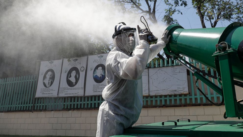 A worker in protective suit controls a big disinfectant spray as they sanitize a school which has suspended classes as a precautionary measure against a new coronavirus in San Juan city, east of Manila, Philippines on Monday, March 9, 2020. Philippin
