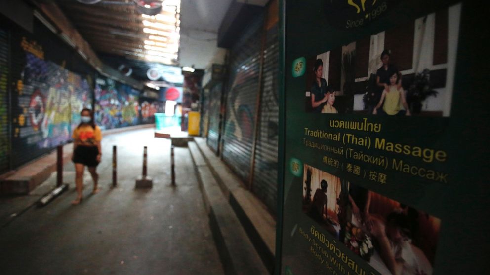 A passerby wearing a face mask to help curb the spread of the coronavirus moves past a closed massage shop in Khao San road, a popular hangout for Thais and tourists in Bangkok, Thailand, Monday, April 26, 2021. Cinemas, parks and gyms were among ven