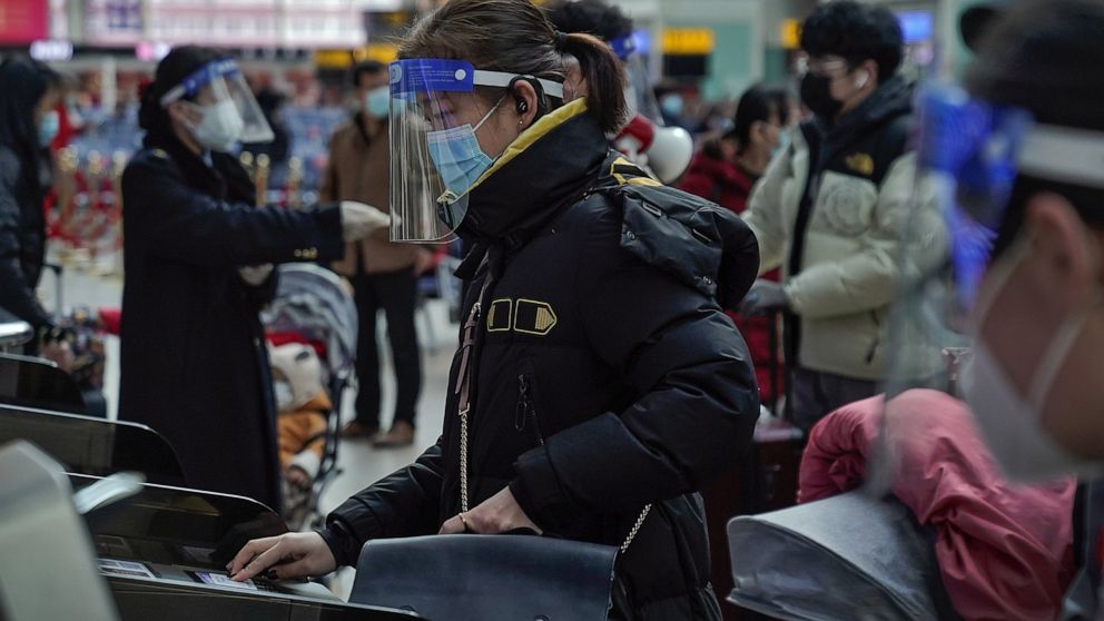 A woman wearing a face mask and face shield to help curb the spread of the coronavirus prepares to board her train at the South Train Station in Beijing, Thursday, Jan. 28, 2021. Efforts to dissuade Chinese from traveling for Lunar New Year appeared 