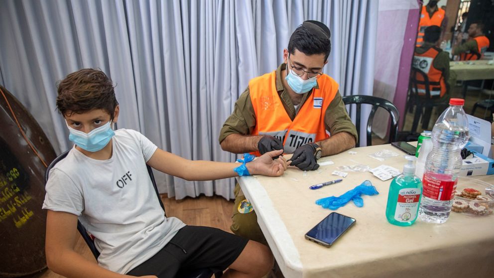 An Israeli soldier conducts a COVID-19 antibody test on a boy in Hadera, Israel, Monday, Aug. 23, 2021. Ahead of the opening of the school year on Sept. 1, the Israeli army's Home Front Command is conducting serology tests on children age 3-12 who ha