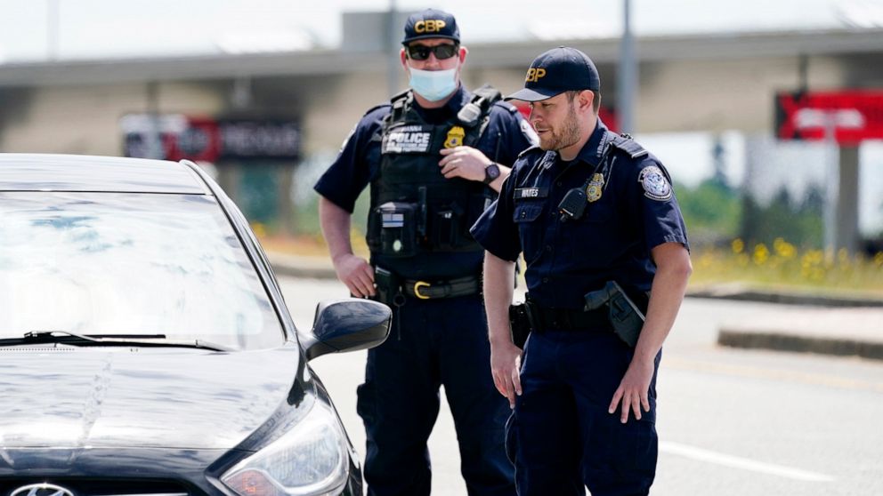 Customs and Border Protection officers direct a driver on who missed the last turn before entry into Canada on how to turn around at the Peace Arch border crossing into the U.S., Tuesday, June 8, 2021, in Blaine, Wash. The border has been closed to n