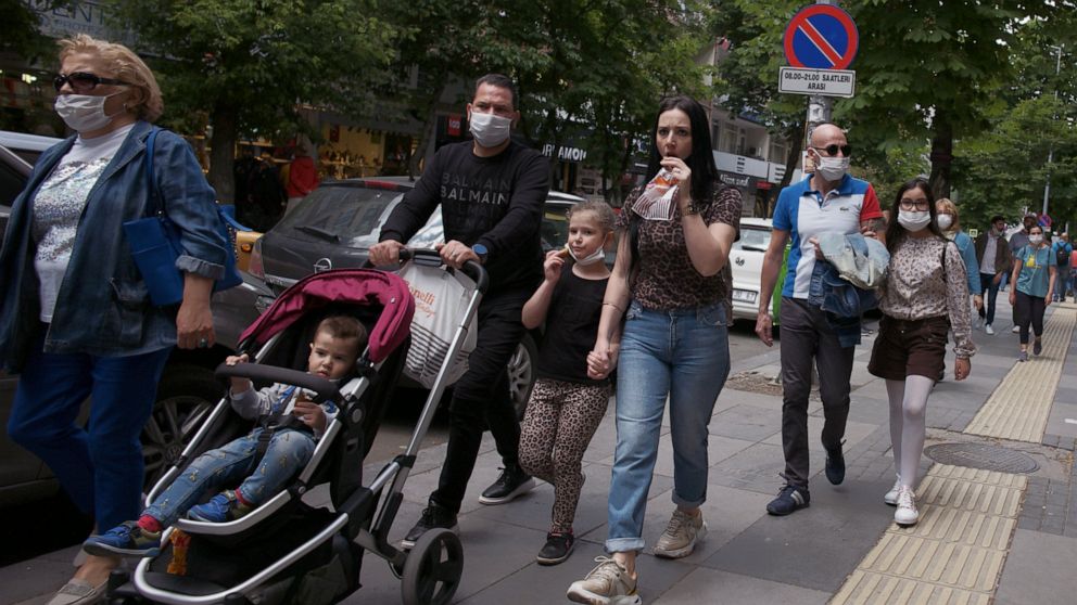 Turkish children under 14 with their parents wearing face masks for protection against the coronavirus, walk in popular Tunali Hilmi Street, in Ankara, Turkey, Wednesday, May 27, 2020. Children were allowed to go out between 12:00-15:00 local time fo