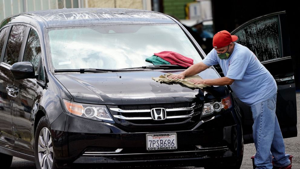 FILE - In this May 20, 2021, file photo, a worker wears a mask as he dries a car amid the COVID-19 pandemic at hand car wash shop, in Los Angeles. California workplace regulators are considering Thursday, June 3, 2021, whether to end mask rules if ev