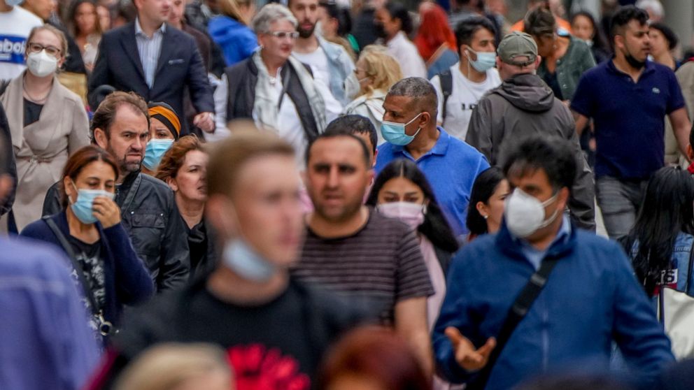 People, some with face masks and some without, walk on a main shopping street in Frankfurt, Germany, Wednesday, July 14, 2021. (AP Photo/Michael Probst)