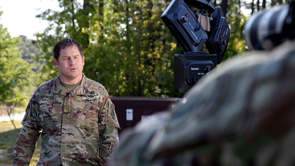 In this Thursday, April 16, 2020 photo, U.S. Army Major Brian Minietta records a weekly Facebook message outside the headquarters of the 3rd Special Forces Group at Fort Bragg, N.C. Since the start of the coronavirus pandemic, the Group Chaplain has 