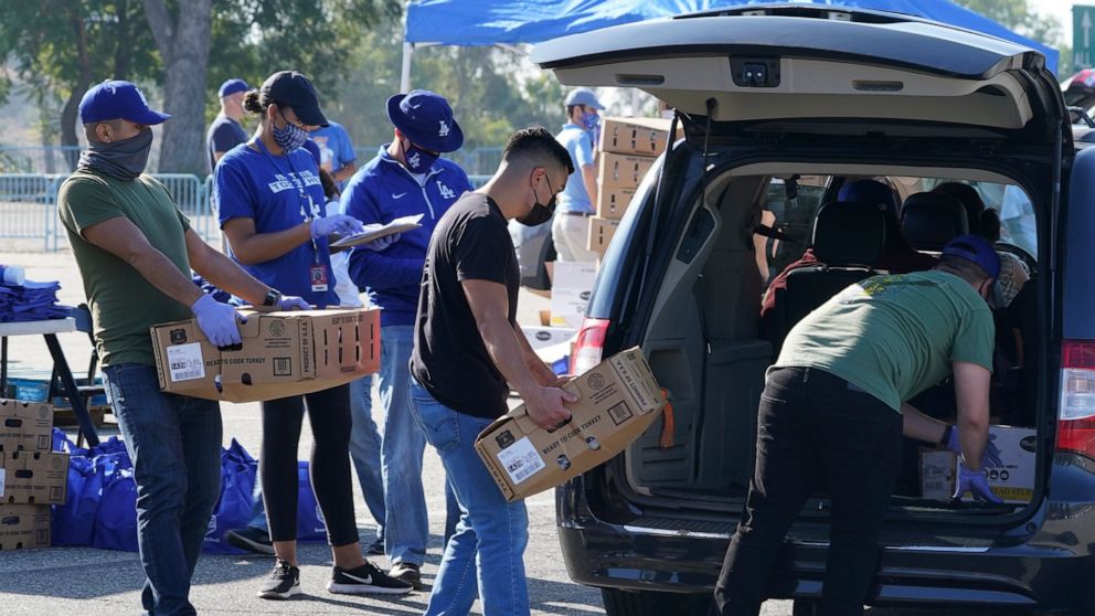Volunteers help distribute some 1,500 Thanksgiving meals, including an assortment of dinner fixings at a drive-thru to not-for-profit community organizations at Dodger Stadium parking lot in Los Angeles Thursday, Nov. 19, 2020. Los Angeles Dodgers, t