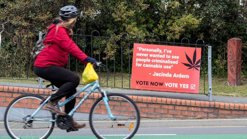 FILE - In this Oct. 15, 2020, file photo, a cyclist rides past a sign in support of making marijuana legal in Christchurch, New Zealand. New Zealanders have voted on Friday, Oct. 30, 2020 in favor of legalizing euthanasia in a binding referendum. But