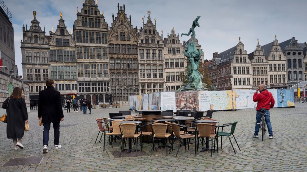 FILE - In this Monday, Oct. 20, 2020 file photo, people walk by chairs and tables of an empty terrace in the historical center of Antwerp, Belgium. Belgian health authorities warned Friday, Feb. 26, 2021 that the number of coronavirus infections is r