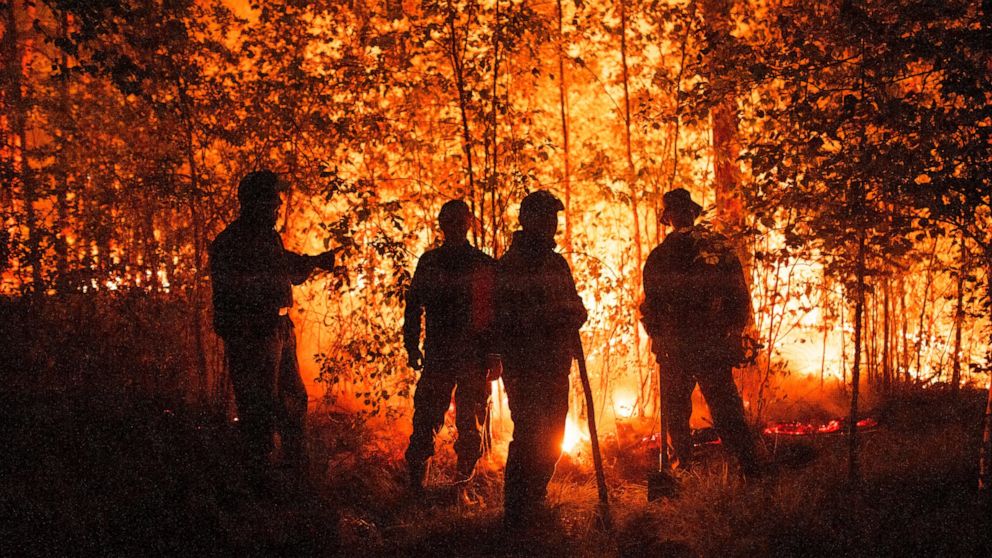 FILE -Firefighters work at the scene of forest fire near Kyuyorelyakh village at Gorny Ulus area, west of Yakutsk, in Russia Thursday, Aug. 5, 2021. A warming planet and land use changes mean more wildfires will scorch large parts of the globe in com