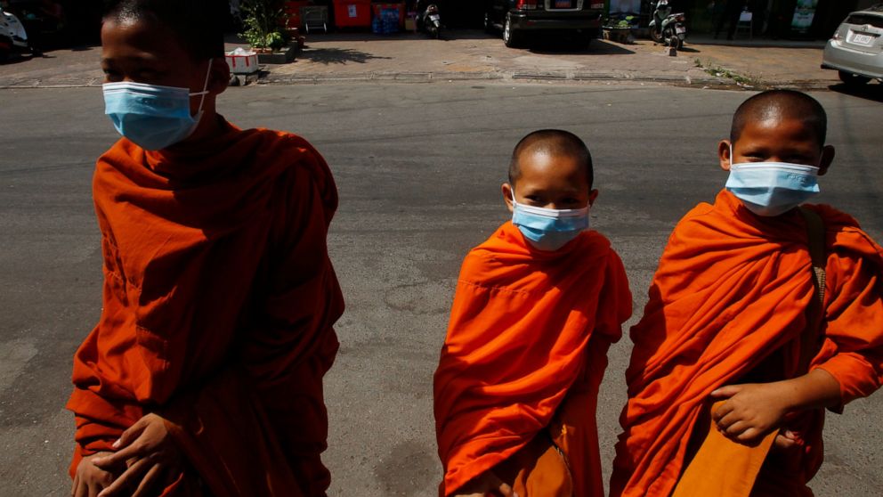 Buddhist monks wearing face masks receive alms from devotees in Phnom Penh, Cambodia, Wednesday, March 10, 2021. (AP Photo/Heng Sinith)
